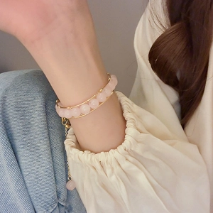 Detail of pink beaded gold bracelet on wrist with elegant butterfly charm and extension chain