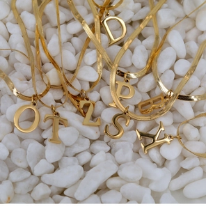 Macro shot of 18K gold plated herringbone chains with various initial letter pendants