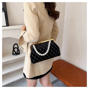 Detail of velvet shell bag featuring diamond quilting, small rhinestones, and pearl handle