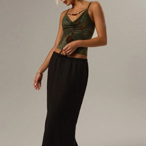 Detail eines dunkelgrünen floralen Camisole-Tops mit schwarzem Maxirock am Modell