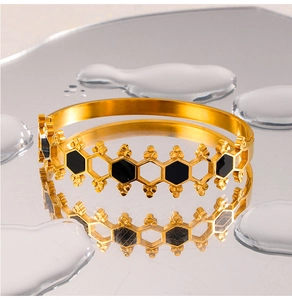 Close-up of golden titanium steel bangle with black honeycomb hexagonal patterns
