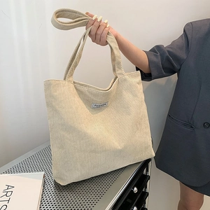 Detail of off-white corduroy tote bag showing striped texture and Fashion woven label