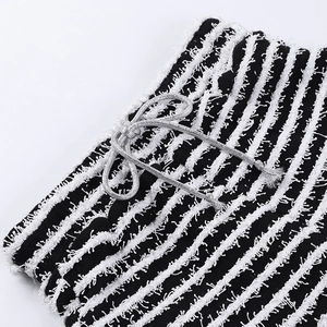 Gros plan sur un tissu tricoté à rayures noires et blanches avec franges et cordons argentés