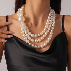 Detail of elegant three-layer faux pearl necklace with large pearl accent on model