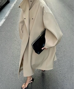 Détail du trench-coat long beige minimaliste avec col montant et silhouette élégante