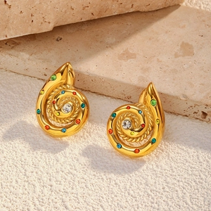 Macro shot of 18k gold plated spiral stud earrings with colorful rhinestones on stone