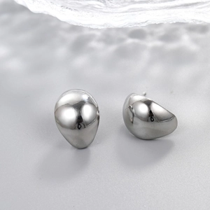 Macro view of water drop stud earrings featuring a polished silver metallic mirror finish