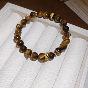 Macro view of tiger eye beads with golden hollow charm on a luxury jewelry box