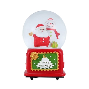 Close-up of a Christmas snow globe with Santa and snowman on a red resin base