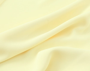 Macro shot of pale yellow midi dress fabric with soft pleated texture and twill weave detail