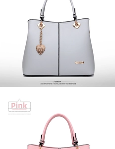 Detail of pink tote bag showing golden heart pendant and black vertical stitching design