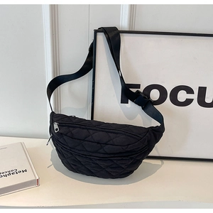 Detail of black quilted fanny pack with adjustable strap and zipper on white surface