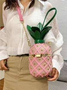 Pink pineapple crossbody bag with gold studs and green leaf top shown on a model