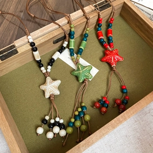 Detail of three colorful ceramic starfish pendant necklaces in a wooden jewelry display box