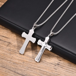 Detail of three-layer stainless steel cross pendant necklace on wood and leather background