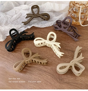 Close-up of matte butterfly claw clips in six colors on a wooden surface with pearls