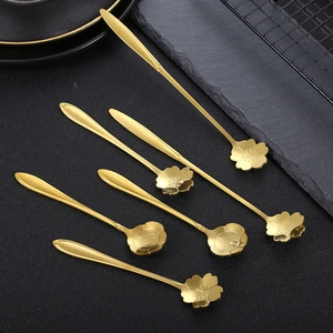 Set of 6 gold flower-shaped stainless steel spoons with long handles on dark slate