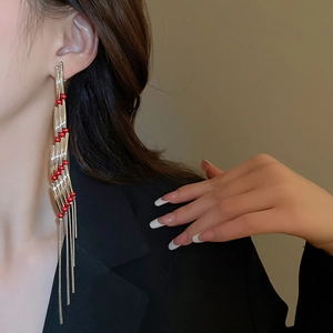 Close-up of long silver fringe earrings with red beads on a model in black blazer