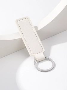 Close-up of a white rectangular leather keychain with silver metal ring and neat stitching