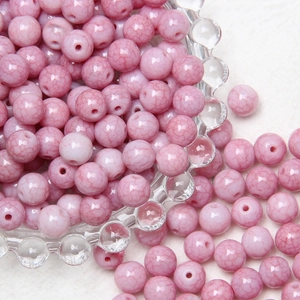 Macro detail of 8mm pink crackle glass beads in a clear bowl for DIY jewelry making