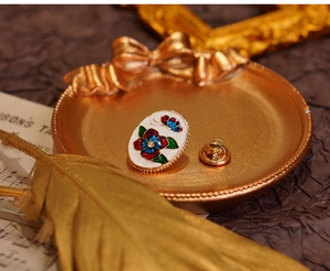 Macro detail of enamel flower brooch with rhinestones and gold butterfly clasp