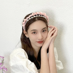 Detail of pink ruffled fabric headband and white pearl hair hoop worn by a model