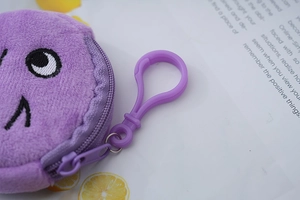 Close-up of purple plush coin purse with matching plastic keychain and cartoon embroidery