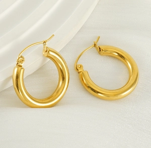 Polished 18K gold round hoop earrings elegantly placed on white silk fabric background