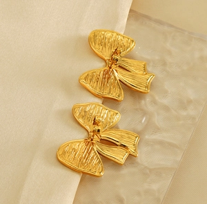 Gros plan détaillé des boucles d'oreilles nœud plaqué or 18K avec texture en métal brossé