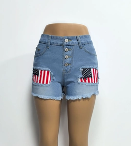 Detail of high-waisted blue denim shorts with American flag patches and ripped fringe edges