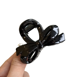 Irregular bow-shaped black shark clip hair claw with glossy finish on white background