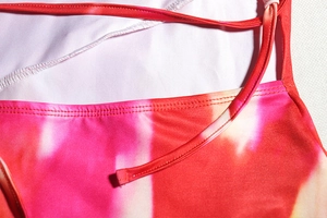 Detail of pink and orange tie-dye print on elastic fabric with durable double stitching