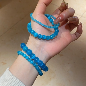Macro shot of blue cat eye stone beaded bracelets in different sizes on female wrist
