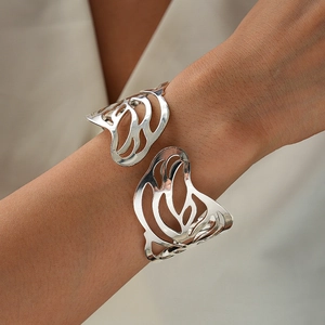 Detailed view of silver hollow butterfly cuff bracelet on female wrist with metallic luster
