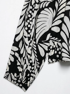 Detail of tropical leaf print on black and white long sleeve top with elastic cuffs