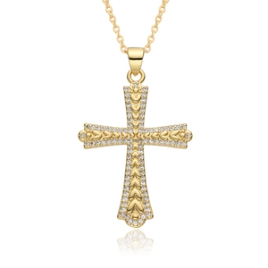Detailed macro view of gold-toned cross pendant with heart patterns and zircon inlay