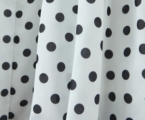 Detailopname van de witte mouwloze jurkstof met zwart polkadotenpatroon voor dames