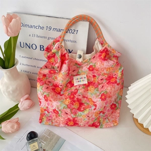 Close-up of floral canvas tote bag with woven handles and metal snap closure