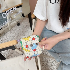 Detailed close-up of a floral mini pouch held by a hand featuring a metal snap closure