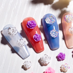 Detailed close-up of 3D resin rose flower nail charms in various colors on long nails