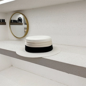 Detailansicht eines flachen Strohhuts mit eleganten schwarz-weißen Satinbändern