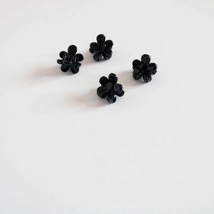 Gros plan de quatre mini pinces à cheveux en forme de fleur noire pour coiffer la frange