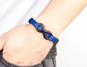 Detail view of a blue braided leather bracelet with a black metal infinity clasp on a wrist