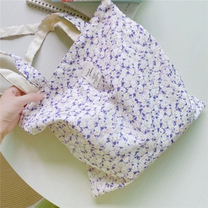 Detailed macro view of floral print canvas tote bag with woven straps and brand label