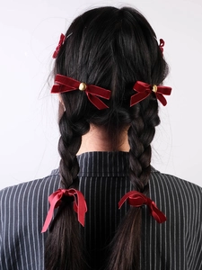 Detailed back view of four red velvet bows styled on braided hair with gold accents