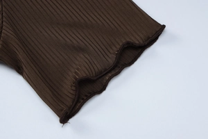 Detail of dark brown knitted dress featuring vertical ribs and lettuce edge sleeve cuff