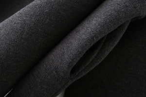Detail of dark grey knit fabric texture showing seamless side pocket and soft fiber finish
