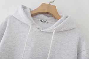 Detailed close-up of grey hooded sweatshirt neckline with drawstring on wooden hanger
