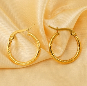 Detail of 18K gold hoop earrings with spiral texture on elegant silk background