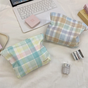 Flat lay of plaid large capacity makeup bags with zipper closure on white linen